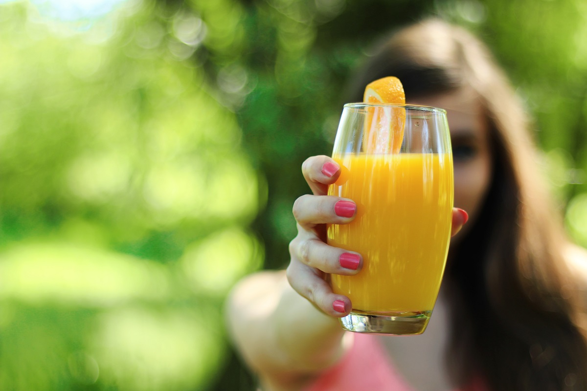 woman holding glass of orange juice
