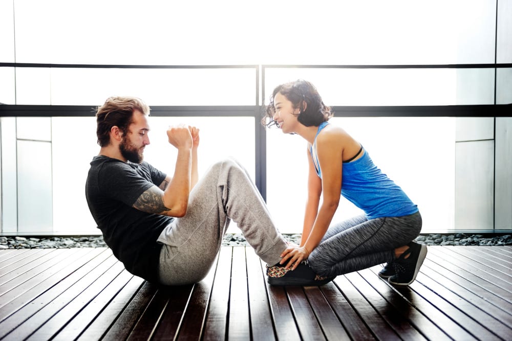 Man doing a sit up while woman holds his feet.